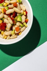 homemade bean salad with carrots, avocado, Purple cabbage, pepper,corn and olive oil and lemon juice on colorful background. Vegan food.Healthy food concept