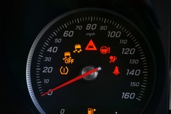 Close up of speedometer dial with warning lights on a car