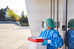 Doctor or surgeon with organ transport after organ donation for surgery in front of clinic entrance in protective clothing