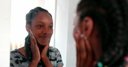 Confident teen adolescent black girl looking herself at mirror