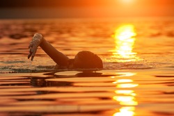 Woman swimming in sunset sunrise time.