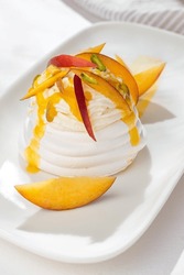 Dessert Pavlova of meringue with passion fruit, nectarines and pistachio on white background for restaurant menu.
