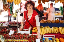 Mature age fruit market saleswoman selecting fresh fruit and preparing for working day.