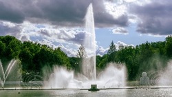 Water from the fountain. Top of high water stream of fountain behind cloudy sky. Fountain in river against dramatic sky.