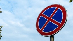 Round road sign with a red cross on a blue background. A sign means a parking prohibition.