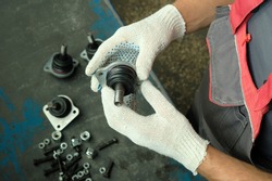 A mechanic examines a set of ball bearing pins before installing them on the car. Repair and maintenance of transport in the service center.