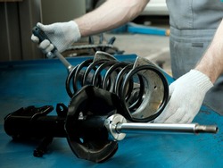 Car spare parts.The mechanic performs the work of replacing the spring and shock absorber of the front suspension strut of the car.Repair and maintenance in a car service station.