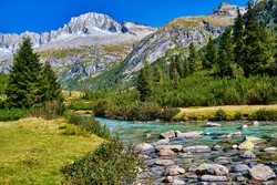 Magic montain river with summer mountains in Val di Fumo, in Adamello-Brenta National park. Blue sky upon a beautiful italian Dolomites mountains landscape with forest. Italian tourism