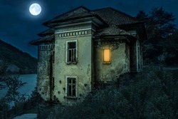 Ancient creepy house with spooky deails in the moonlight with dark horror atmosphere. Haunted house scene like in Halloween movies. Old frightful abandoned manor with full moon in the ghost tour