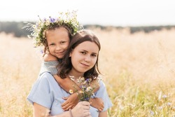 Two sisters older and younger play in the field with flowers