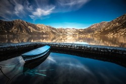 Kotor bay with beautiful reflections on water and fishing boats mountaind and colorful sky