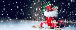 Santa Claus boots with gift box, candy canes and gingerbread cookies in the snow - Christmas background banner with copy space