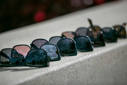 Men's sunglasses of various shade lined up on a concrete wall