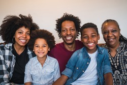 Portrait of african american multigenerational family looking at camera while sitting on sofa couch at home. Family and lifestyle concept.
