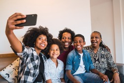 Portrait of african american multigenerational family taking a selfie together with mobile phone at home. Family and lifestyle concept.