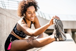 Afro athlete woman stretching legs before exercise.