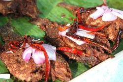 Deep fried fish with chili and onions on banana leaves. Thai street food