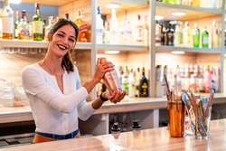 Attractive female bartender preparing a cocktail in a pub
