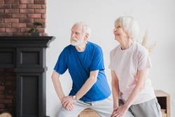 Caucasian senior old elderly healthy grandparents couple stretching together at home indoors, doing fitness exercises,, keeping body fit, in perfect shape. Active seniors