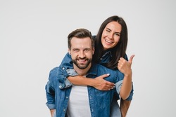 Young happy caucasian couple spouses girlfriend and boyfriend doing piggyback, dating, sharing love and passion showing thumb up isolated in white background