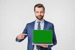 Caucasian young confident businessman pointing showing at computer laptop screen with green mockup copyspace for e-learning, remote work, application online isolated in white background