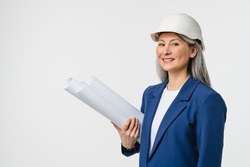 Successful middle-aged mature female engineer architect foreman in white hard hat holding architectural plans for new house building, real estate agent isolated in white background