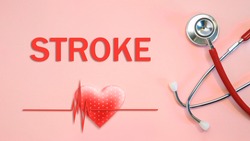 STROKE concept with stethoscope and heart shape on a red background