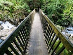 Forest wooden bridge over mountain river. Wairere falls track