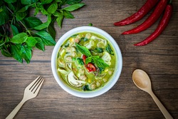 Vegetarian Thai Green Curry in bowl at wood slate background. Veg Green Thai Curry is thailand cuisine dish with green chillies paste, basil, spices and vegetables. Thai Food top view