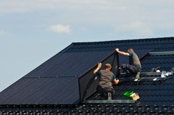 Installing new black solar panels on the metal roof of a private house. Ecology, renewable energy and green sustainable source of power abstract.