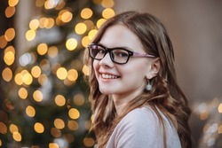 Portrait of a smiling girl on the background of a New Year tree at Christmas.