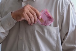 Close-up: A man's hand tucked money in his shirt pocket.