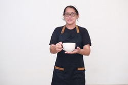 A woman wearing a black apron over a black t-shirt serves a large cup of coffee to her customers with a smile.