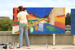 Artist painting on a wooden plywood canvas at an outdoor festival