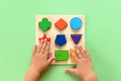 The child collects a multicolored wooden sorter. Educational logic toy for kid's. Top view.