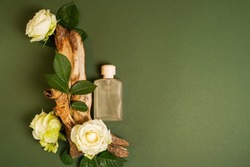 Perfume on tree bark with flowers roses on green background with copy space. concept of freshness and naturalness. the aroma of wood