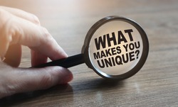 What makes you unique question under magnifying glass. Career business concept.
