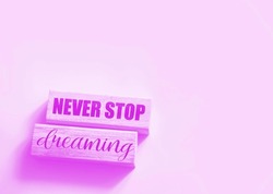 Never stop dreaming words printed on wooden blocks on soft pink. Positive thinking mindset concept