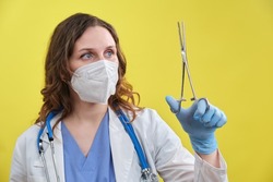 The doctor holds a surgical clamp in his hand. Nurse with a medical clip with scissors in her hand, studio background