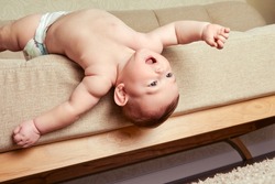 Infant baby falls off the sofa in the home living room. Toddler kid gets off the bed. Problems with the safety of children without parental supervision