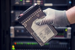 A hard disk for a raid in the hands of a man at a data storage server, close-up