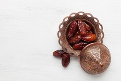 Plate of pitted dates on a white wooden background. Top view
