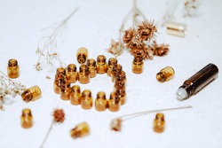 1ml amber glass vials arranged in love heart shape with dried flowers and roller bottles. Natural health and wellness background image.