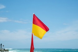 Lifeguard flag flying on the beach at Port Campbell on the Great Ocean Road, Victoria Australia with blue sky in background