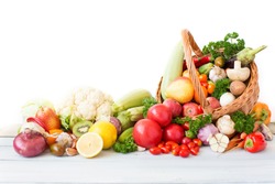 Fresh vegetables and fruit in basket on white background.