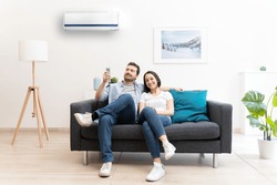Happy couple freshen up using air conditioner at home