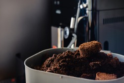 Used coffee grounds from espresso machine. Recycling compost container filled with used coffee waste. Coffee machine cleaning.