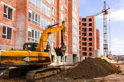 A crawler excavator is working on a construction site. Laying communication to multi-storey buildings.