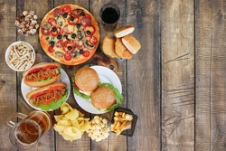 Fast food on old wooden background. Concept of junk eating. Top view. Flat lay.