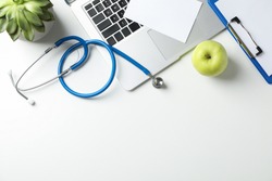 Stethoscope, apple, laptop and plant on white background, top view. Doctor workplace